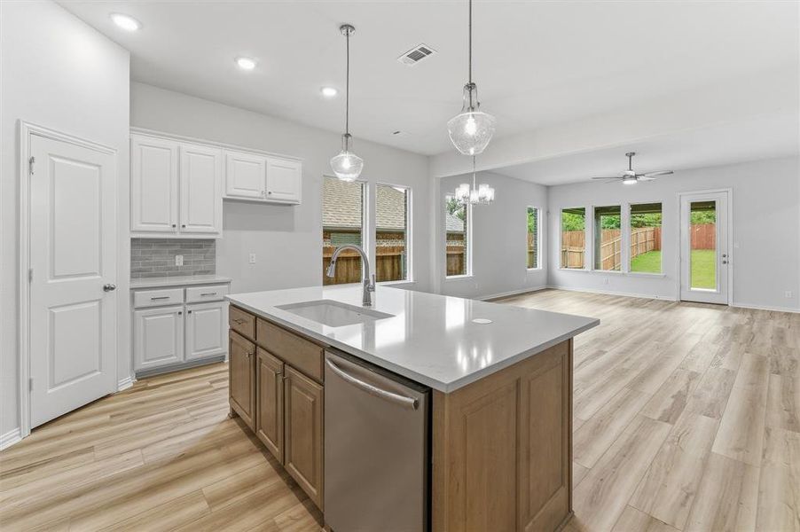 Spacious kitchen island featuring a deep undermount sink, stainless steel dishwasher, and quartz countertop