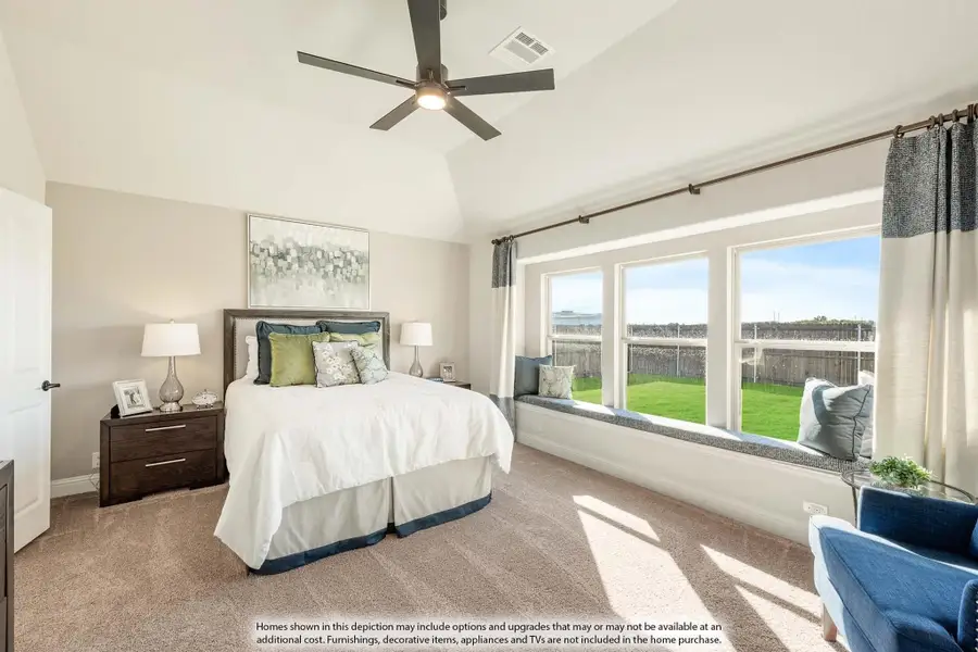 Bedroom with vaulted ceiling, ceiling fan, window seat, and large windows overlooking a backyard