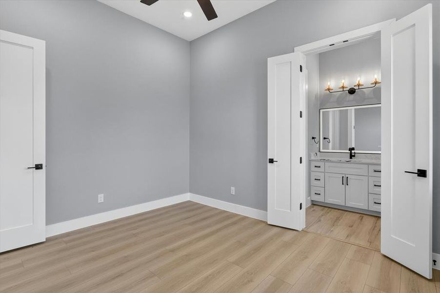 Light wood-finish flooring extending into a bathroom with a white vanity featuring multiple drawers and cabinet storage
