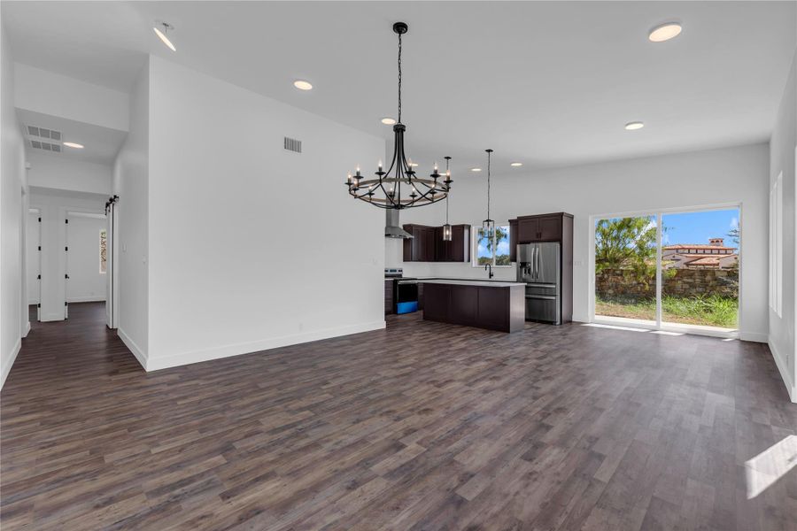 Recessed lighting illuminates wood-look flooring and sliding glass doors in a modern open layout.