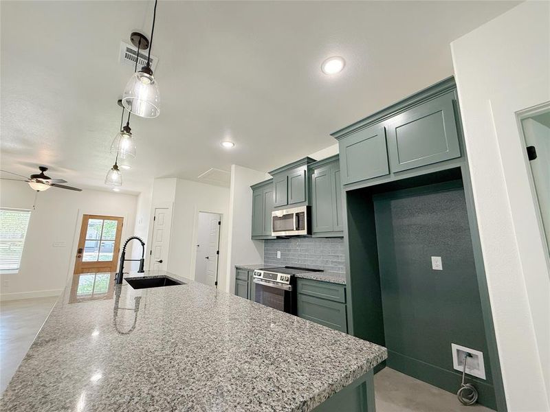 Kitchen featuring visible vents, baseboards, green cabinetry, a sink, and appliances with stainless steel finishes Kitchen featuring visible vents, baseboards, green cabinetry, a sink, and appliances with stainless steel finishes