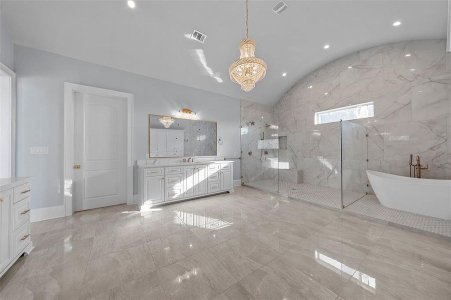 Bathroom with a freestanding bath, vanity, a marble finish shower, lofted ceiling, and light marble finish flooring Bathroom with a freestanding bath, vanity, a marble finish shower, lofted ceiling, and light marble finish flooring