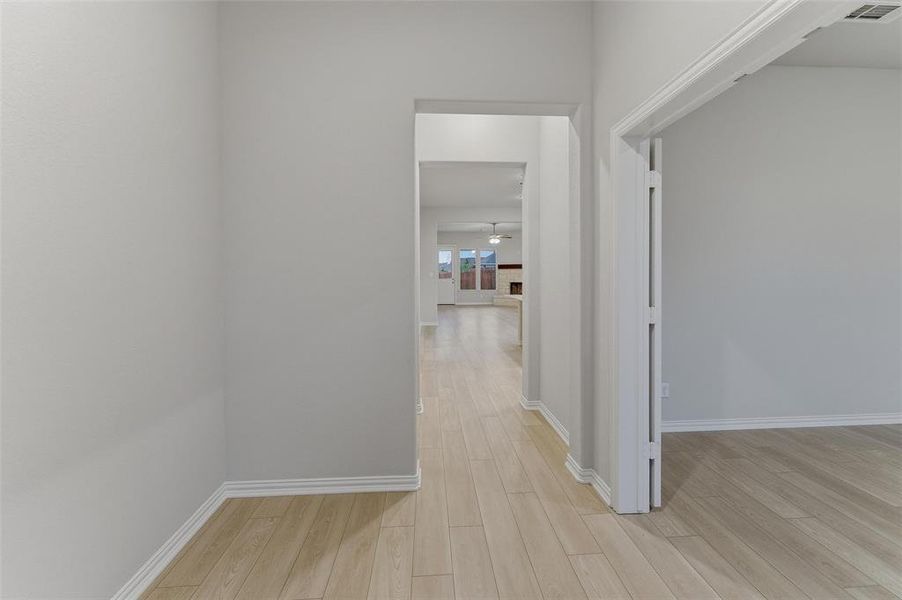 Hallway featuring wood-finish flooring, white baseboards, and light neutral wall paint