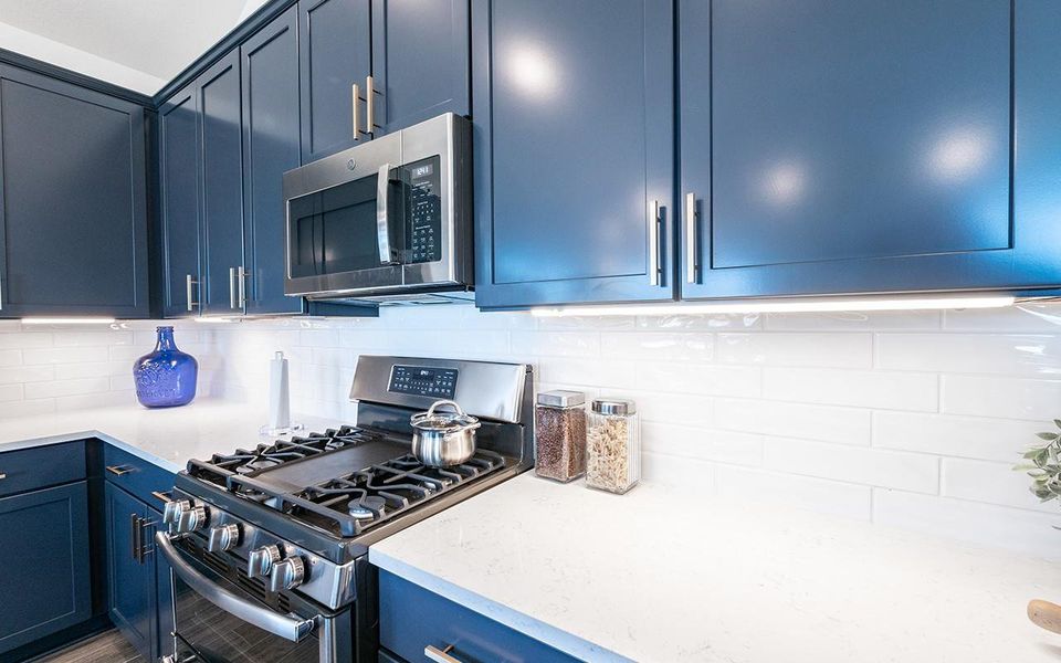 Kitchen with stainless steel appliances, blue cabinets, light countertops, and tasteful backsplash Kitchen with stainless steel appliances, blue cabinets, light countertops, and tasteful backsplash