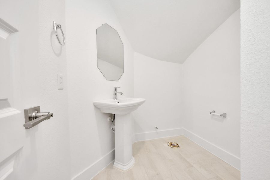 This half bathroom features a stylish pedestal sink, modern hardware, and bright recessed lighting, creating a sleek and inviting space. This half bathroom features a stylish pedestal sink, modern hardware, and bright recessed lighting, creating a sleek and inviting space.