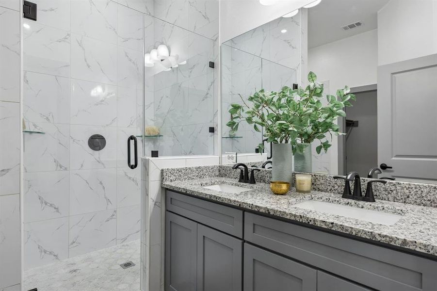 The ensuite primary bathroom features a shower with frameless glass and a vanity with 2 sinks.