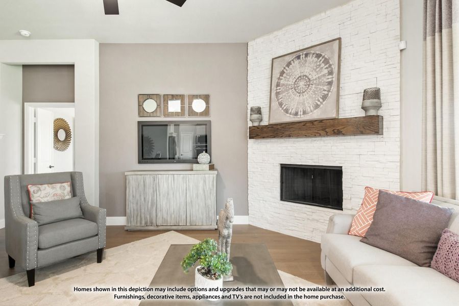 Living room with white stacked-stone fireplace, wood mantel, gray sofa, accent chair, and wall-mounted TV