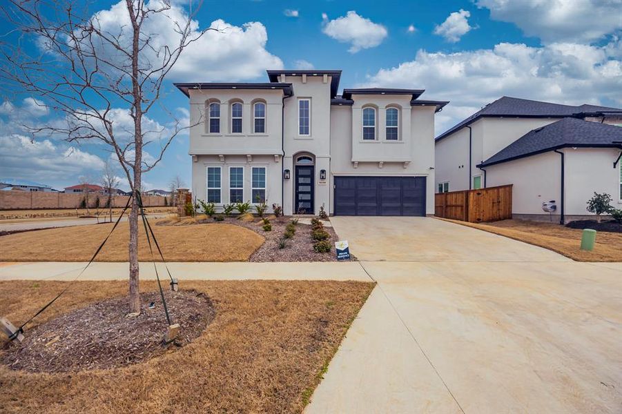 View of front of home with fence, a garage, driveway, and stucco siding