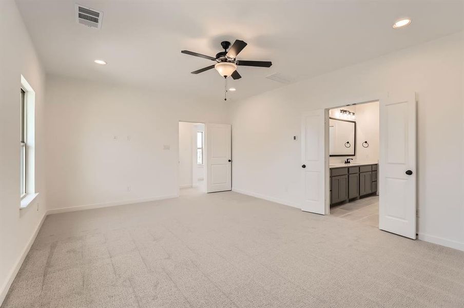 Unfurnished bedroom with light carpet, connected bathroom, ceiling fan, and sink