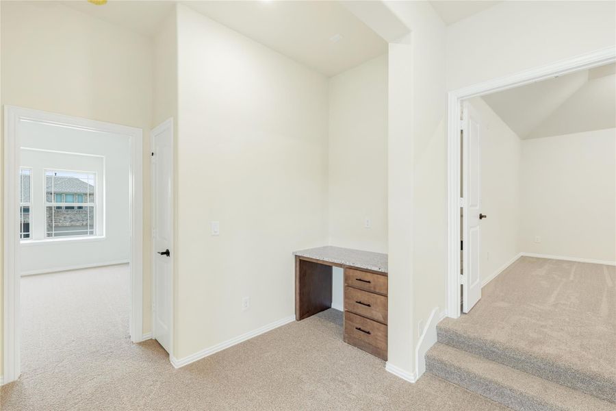 Bedroom or loft area with built-in wood desk, granite top, carpet flooring, and access door with window. Bedroom or loft area with built-in wood desk, granite top, carpet flooring, and access door with window.