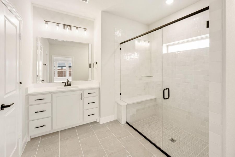 Bathroom with white vanity, large mirror, and walk-in glass shower with bench seat and tile walls