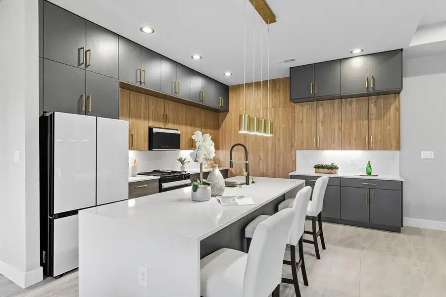 Kitchen with freestanding refrigerator, a kitchen breakfast bar, black gas range, a center island with sink, and modern cabinets Kitchen with freestanding refrigerator, a kitchen breakfast bar, black gas range, a center island with sink, and modern cabinets