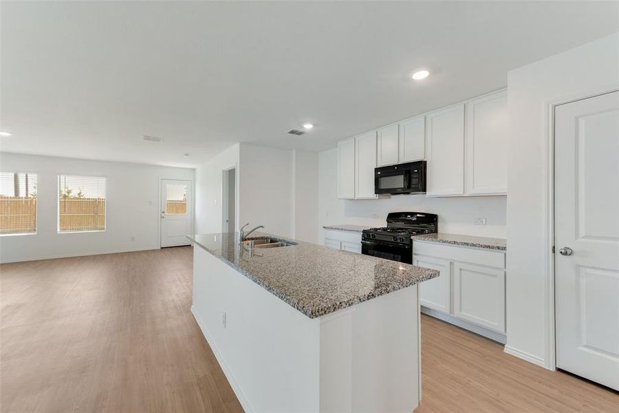 Kitchen featuring light hardwood / wood-style flooring, white cabinets, black appliances, and sink