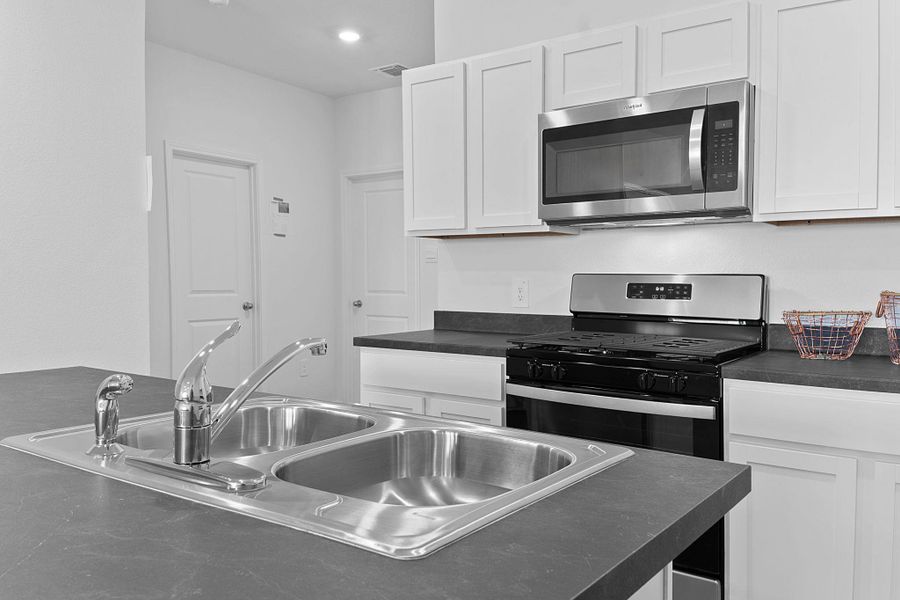 Kitchen featuring dark countertops, visible vents, stainless steel appliances, and a sink