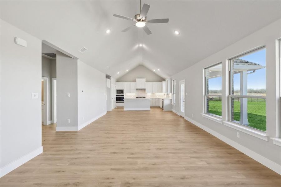 Unfurnished living room with ceiling fan, light hardwood / wood-style flooring, and vaulted ceiling