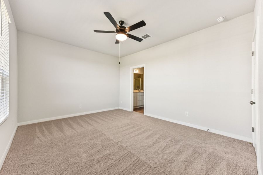 A room with a ceiling fan and carpet.