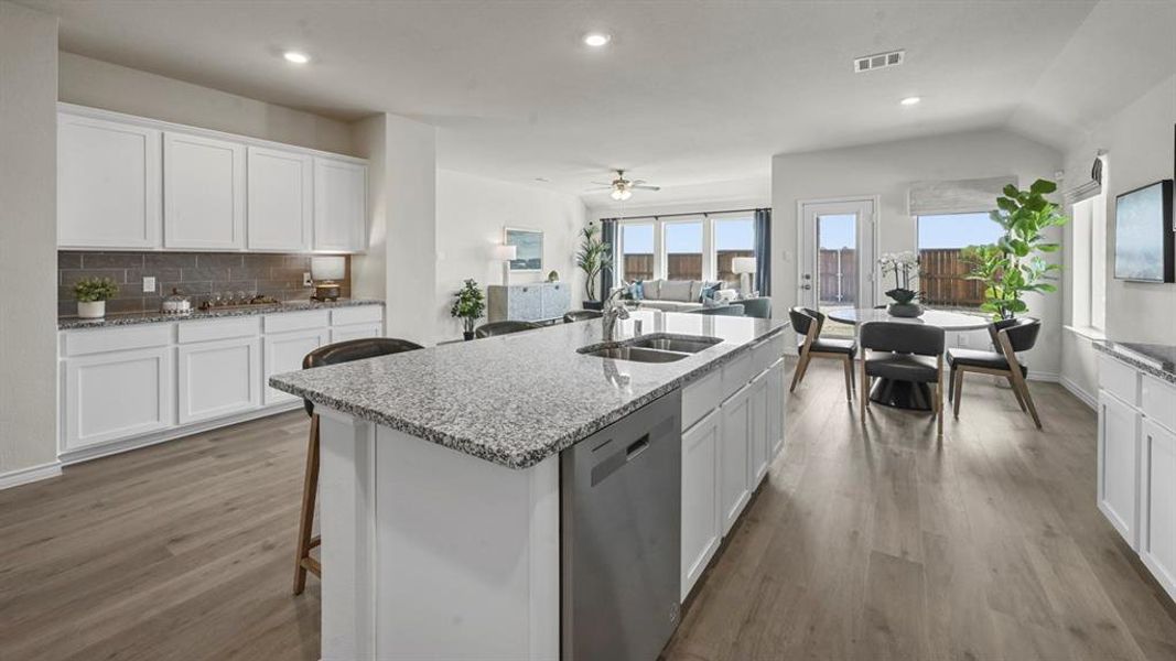 Kitchen featuring white cabinets, a breakfast bar area, a center island with sink, recessed lighting, and backsplash