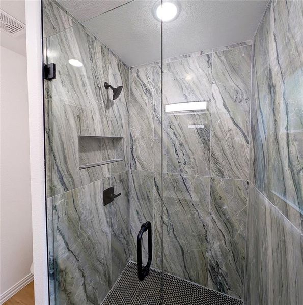 Details with walk in shower and a textured ceiling