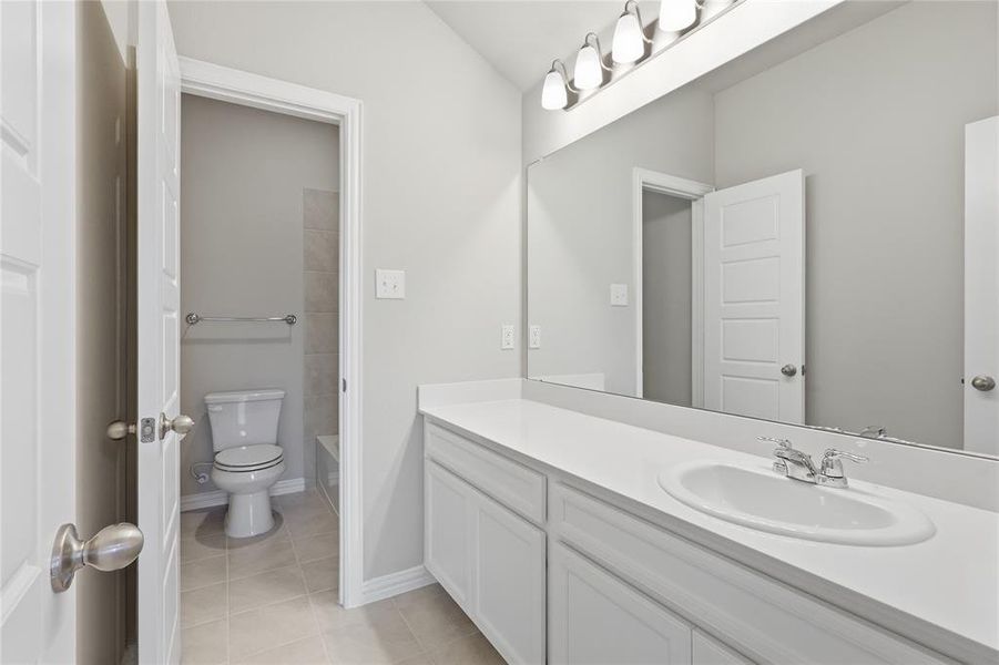 Bathroom featuring a spacious vanity with an integrated sink, polished chrome faucet, and a large wall-mounted mirror