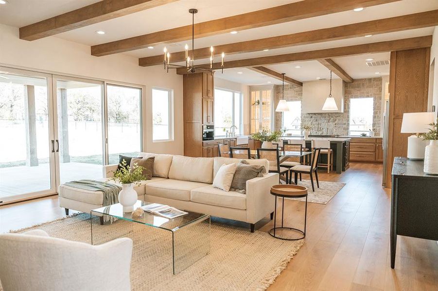 Living area with light wood-type flooring, suspended lighting, and beam ceiling Living area with light wood-type flooring, suspended lighting, and beam ceiling