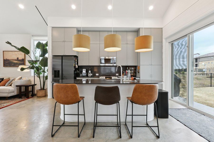 Kitchen featuring concrete floors, a center island with sink, a breakfast bar area, stainless steel appliances, and open floor plan