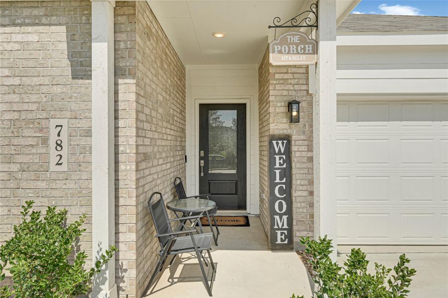 Charming front porch with a cozy seating area, welcoming sign, and stylish brick exterior, perfect for relaxing and enjoying the neighborhood ambiance. Charming front porch with a cozy seating area, welcoming sign, and stylish brick exterior, perfect for relaxing and enjoying the neighborhood ambiance.
