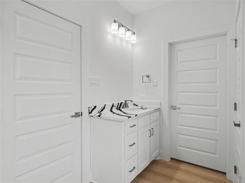Bathroom vanity featuring a white cabinet, integrated sink, and patterned countertop Bathroom vanity featuring a white cabinet, integrated sink, and patterned countertop