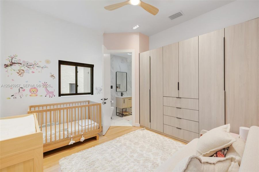 Beautifully appointed secondary bedroom with custom built-in storage, ensuite bath, and warm natural finishes that continue throughout the home.
