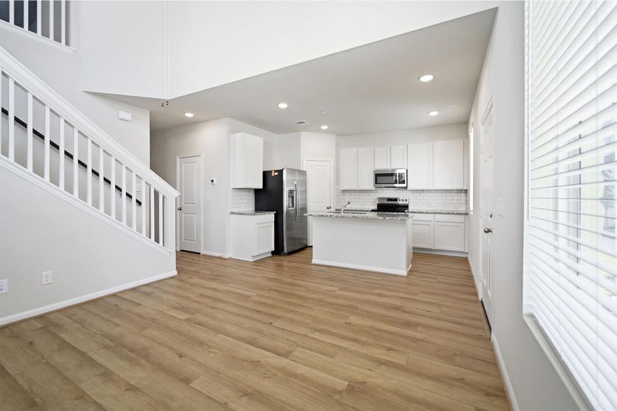 Kitchen featuring white cabinets, an island with sink, stainless steel appliances, light wood-style floors, and recessed lighting