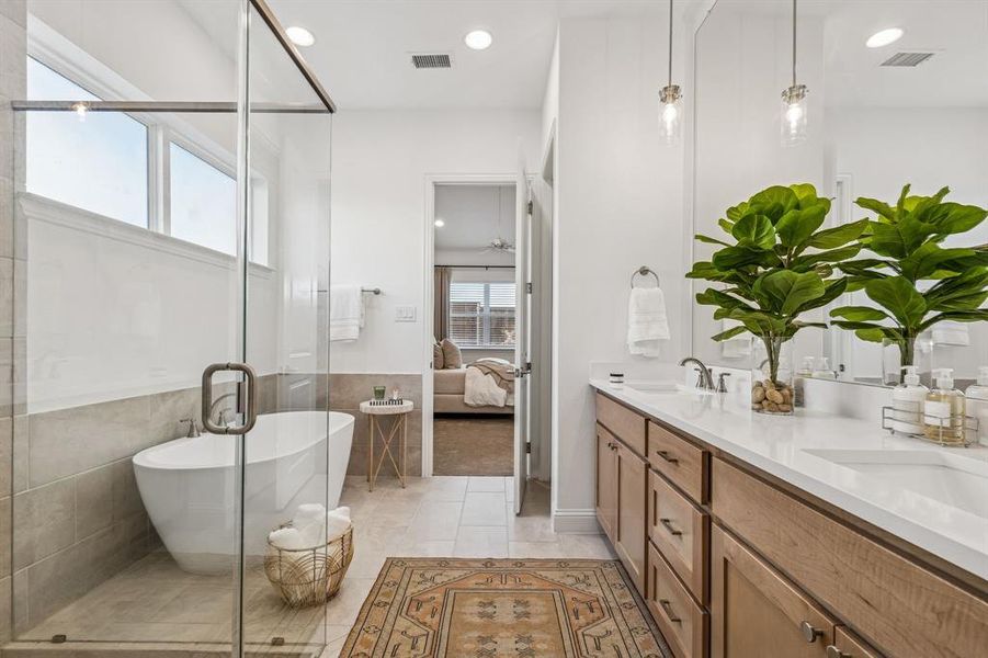 Bathroom featuring ensuite bath, double vanity, a freestanding bath, a stall shower, and recessed lighting