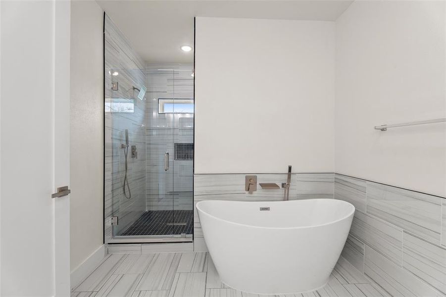 Bathroom featuring a freestanding tub, a shower stall, tile walls, recessed lighting, and a wainscoted wall Bathroom featuring a freestanding tub, a shower stall, tile walls, recessed lighting, and a wainscoted wall