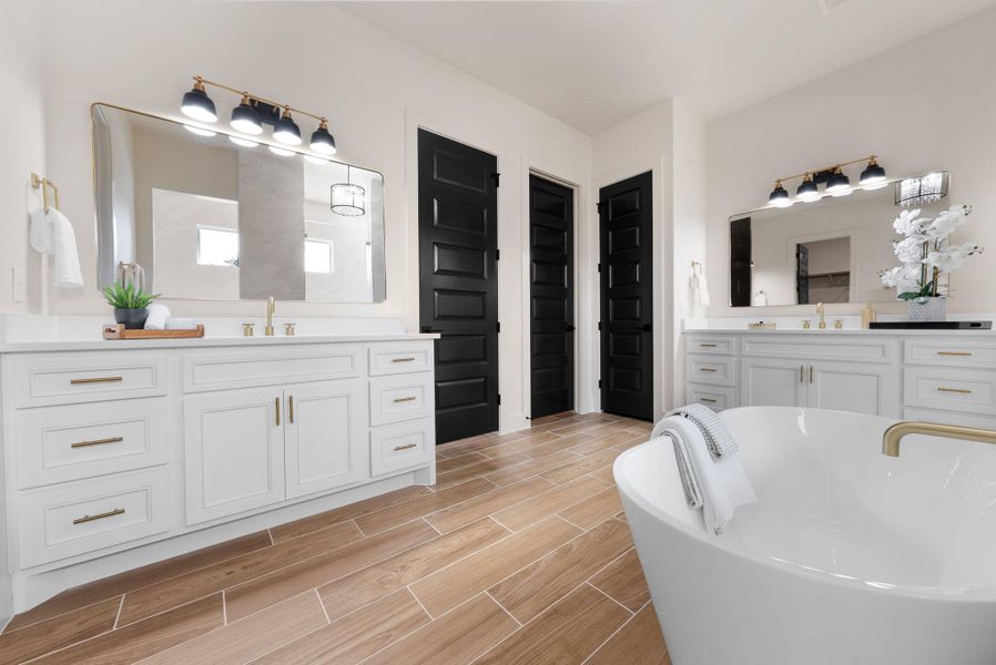 A spacious primary bath showcases a luxurious soaking tub and dual vanities, creating a tranquil retreat.