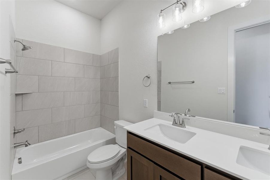 Bathroom featuring a dual vanity with white countertops, wood-finish cabinetry, and brushed nickel fixtures