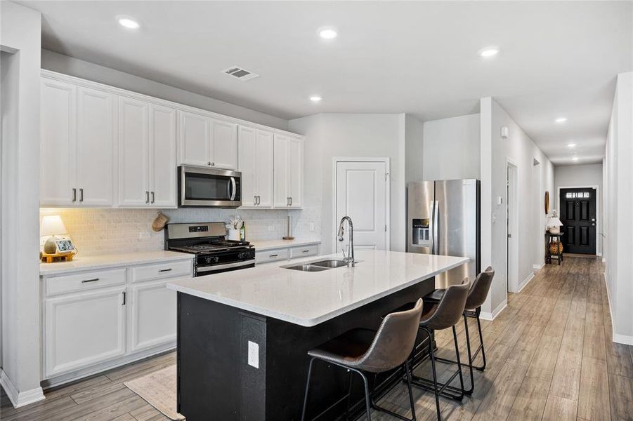 Kitchen with appliances with stainless steel finishes, a kitchen island with sink, decorative backsplash, a breakfast bar area, and recessed lighting