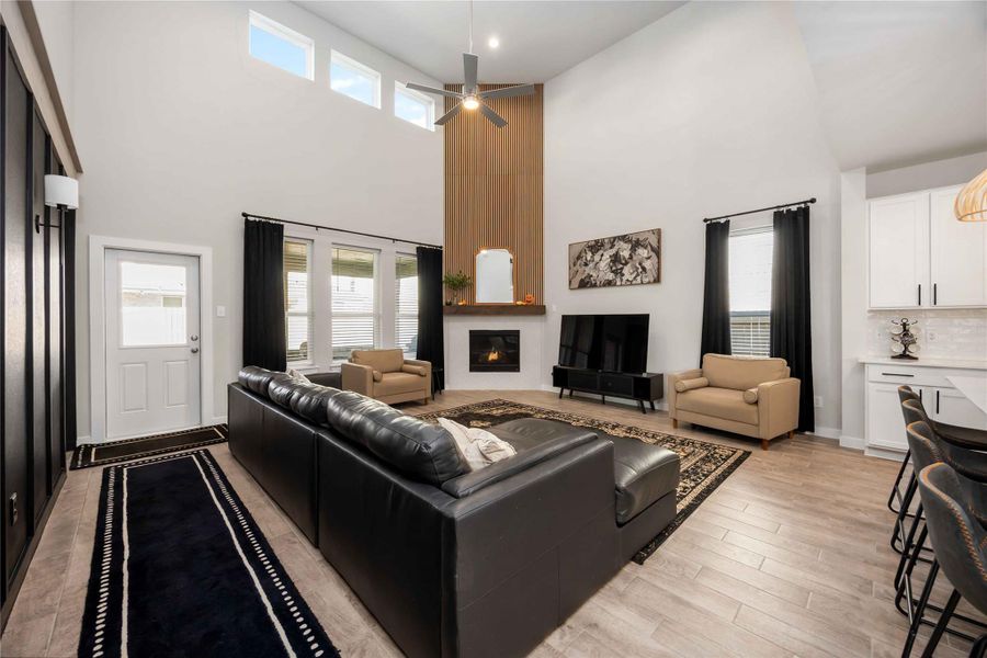 Open-concept living room with soaring ceilings, fireplace, and large windows for natural light. Open-concept living room with soaring ceilings, fireplace, and large windows for natural light.