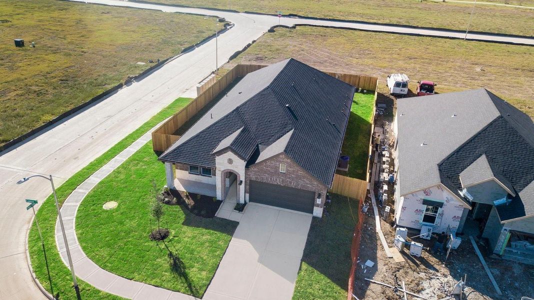 An aerial view of the newly built one story home with traditional architecture, a two car garage and a landscaped front yard