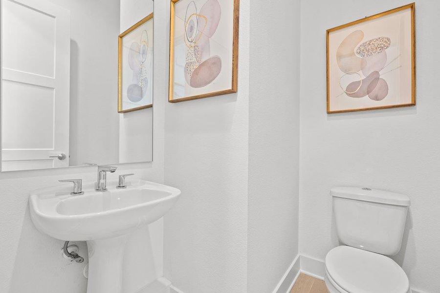A well-appointed powder room features a modern pedestal sink, toilet, and subtle decor. A well-appointed powder room features a modern pedestal sink, toilet, and subtle decor.