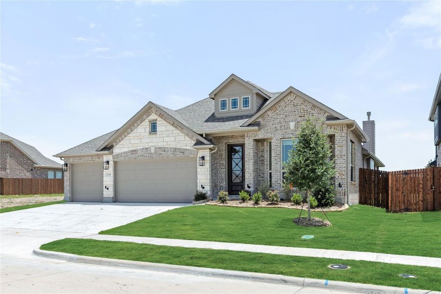 Single-story brick home with two-car garage, dormer window, and manicured front lawn