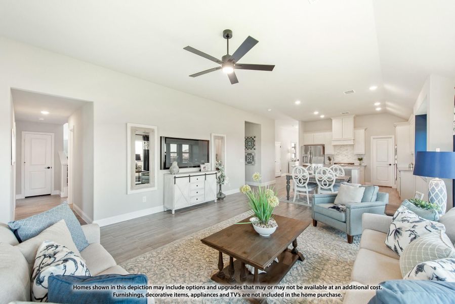 Open-concept living room with hardwood floors, ceiling fan, and view into kitchen and dining area