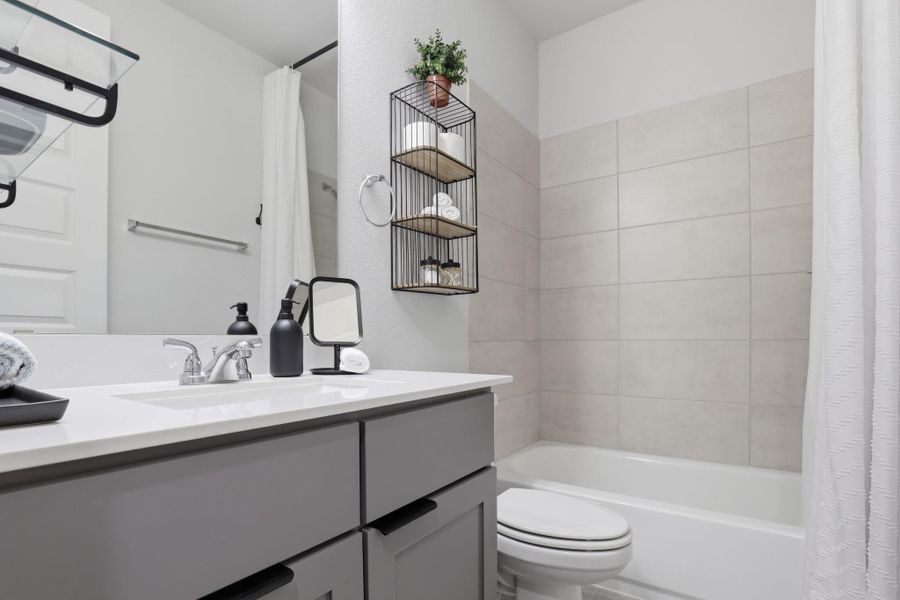 The well-appointed secondary bath is complete with modern cabinetry and updated tile surround.