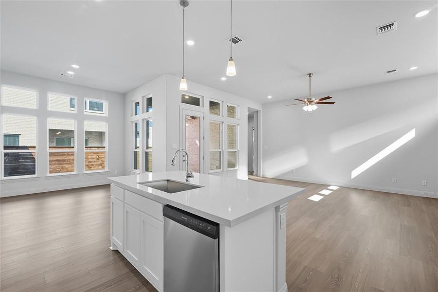 Kitchen with open floor plan, white cabinetry, dishwasher, an island with sink, and hanging light fixtures