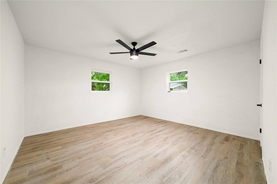 Spare room featuring visible vents, a healthy amount of sunlight, ceiling fan, and light wood-style flooring Spare room featuring visible vents, a healthy amount of sunlight, ceiling fan, and light wood-style flooring