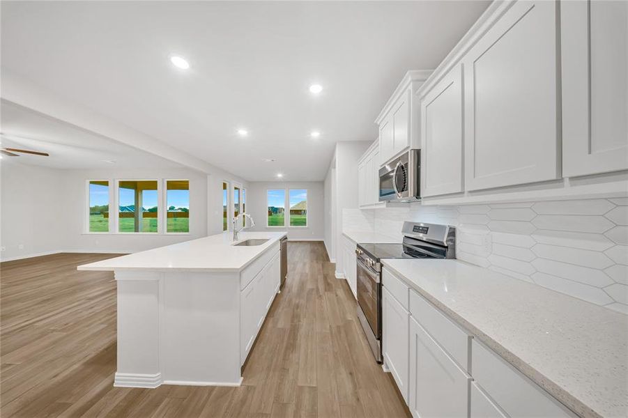 Kitchen with appliances with stainless steel finishes, light wood finished floors, white cabinetry, decorative backsplash, and recessed lighting Kitchen with appliances with stainless steel finishes, light wood finished floors, white cabinetry, decorative backsplash, and recessed lighting