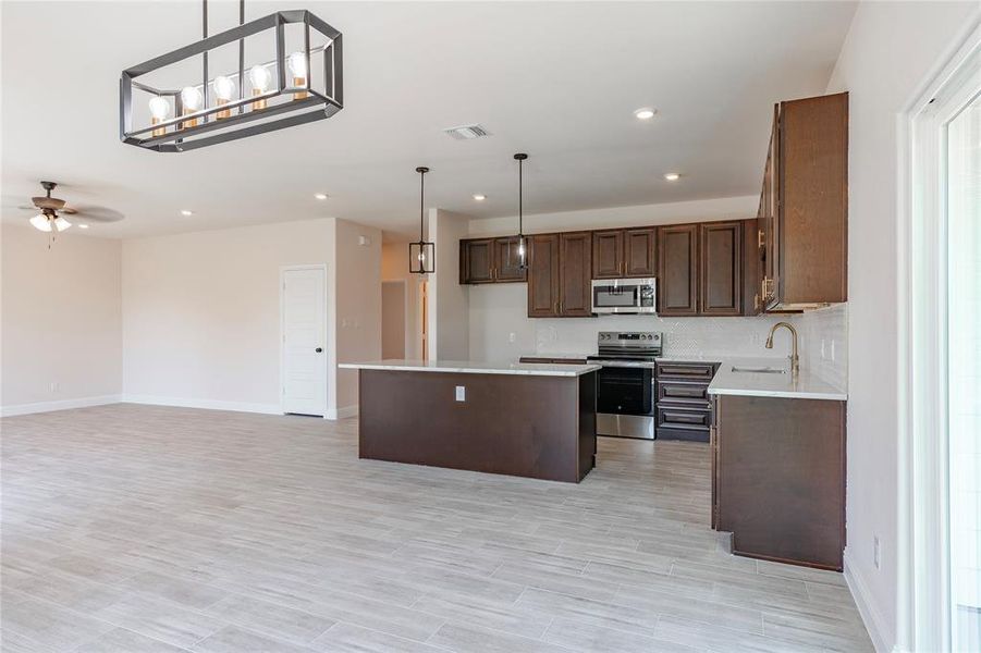 Kitchen with stainless steel appliances, a kitchen island, ceiling fan, sink, and decorative light fixtures