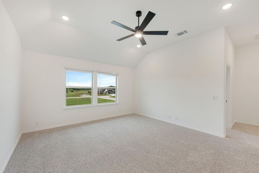 Empty bedroom with vaulted ceiling, black ceiling fan, carpet flooring, and a window with outdoor views