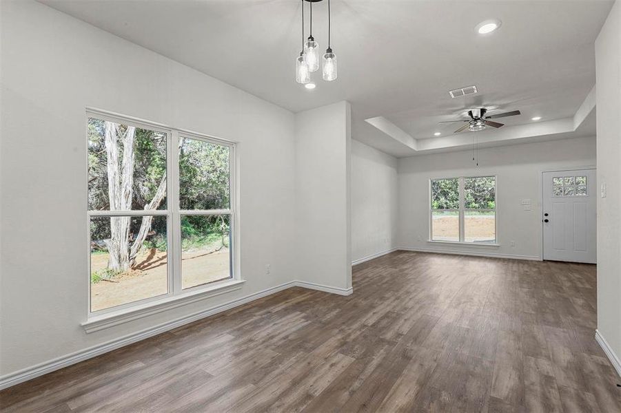 Spare room with ceiling fan, a tray ceiling, and hardwood / wood-style flooring