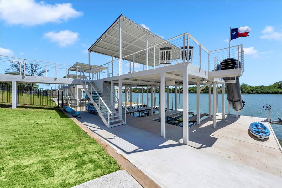 A multi-level boat dock with a covered upper deck overlooks the calm water.