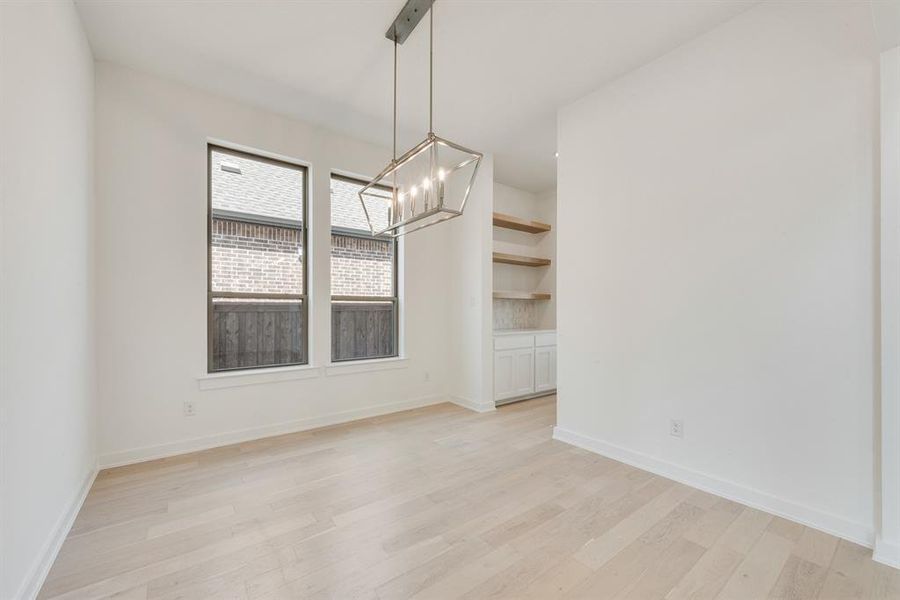 Unfurnished dining area with light wood-style flooring and a chandelier Unfurnished dining area with light wood-style flooring and a chandelier