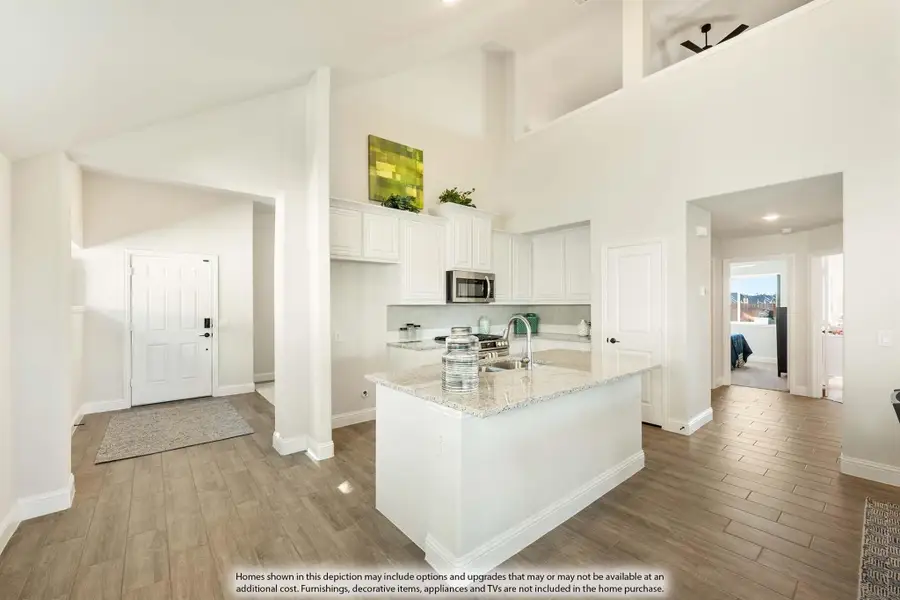 Open kitchen with white cabinets, granite island, and high ceilings with wood-look tile floors