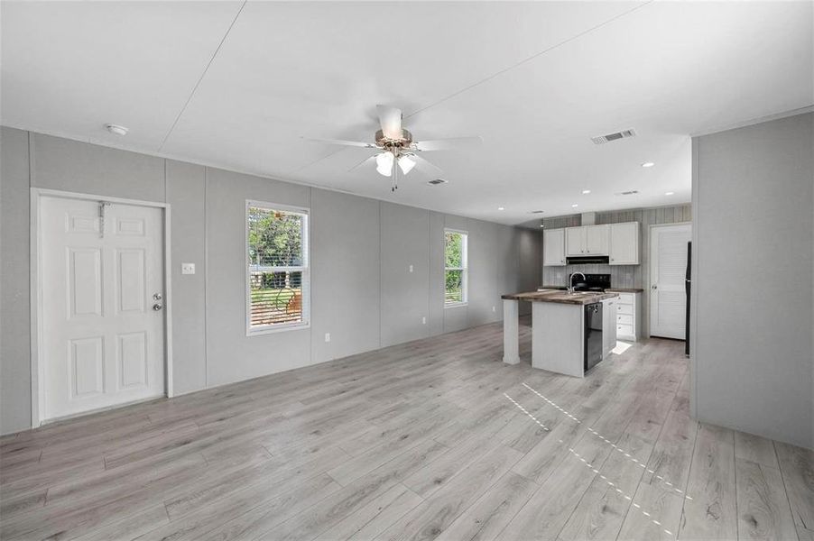 Kitchen with visible vents, under cabinet range hood, open floor plan, light wood-type flooring, and a ceiling fan